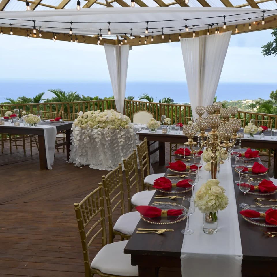 Dinner tables with red napkins and white flowers on the deck at Bay Vista Villa at sunset