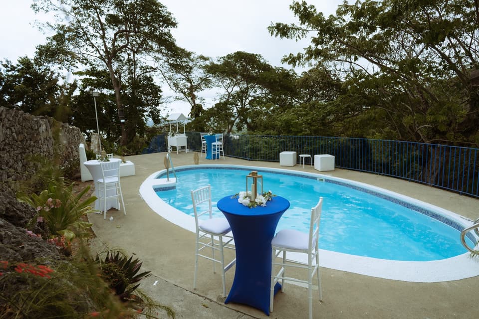 The private pool at Bay Vista Villa with a cocktail table set beside it and trees behind