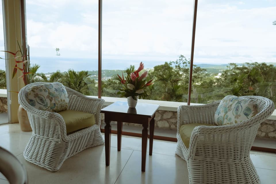 Wicker armchairs and tropical flowers on the veranda at Bay Vista Villa, facing the bay